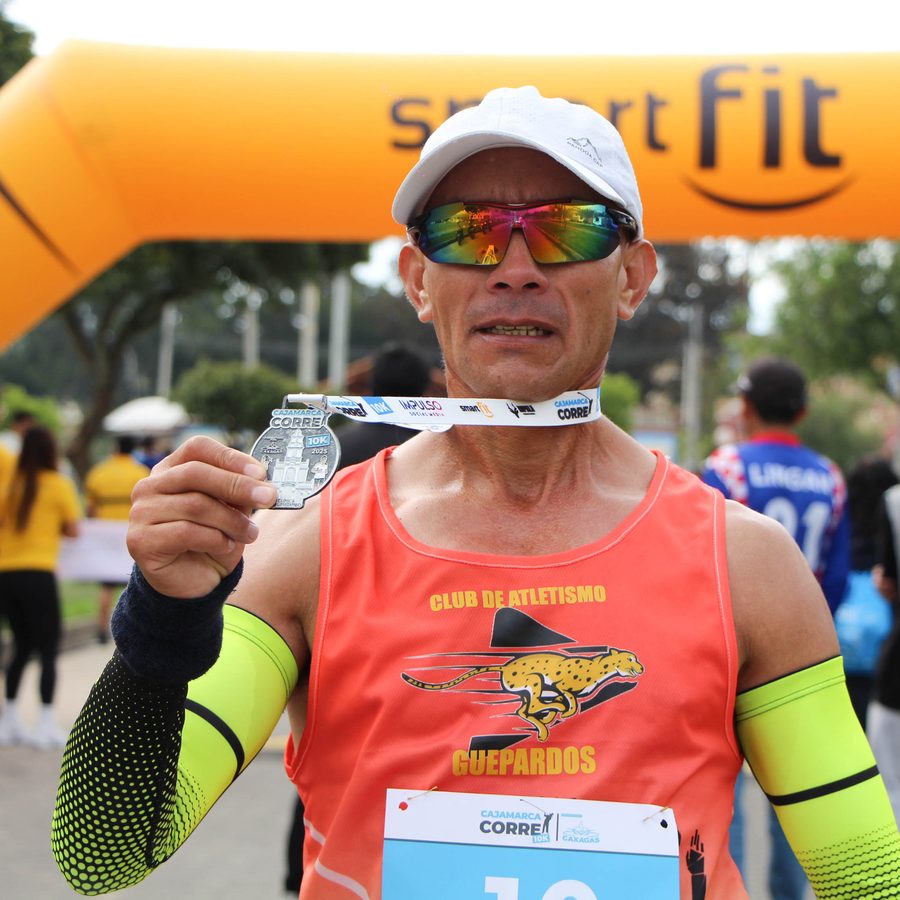 Corredor mostrando su medalla finisher a la cámara