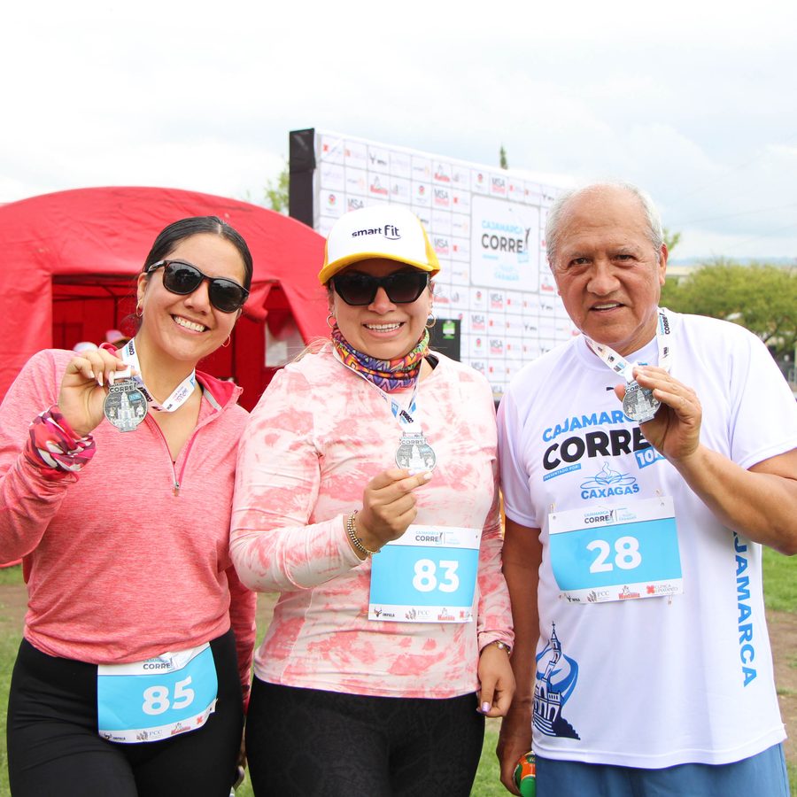 Tres participantes celebrando con sus medallas en la zona de meta